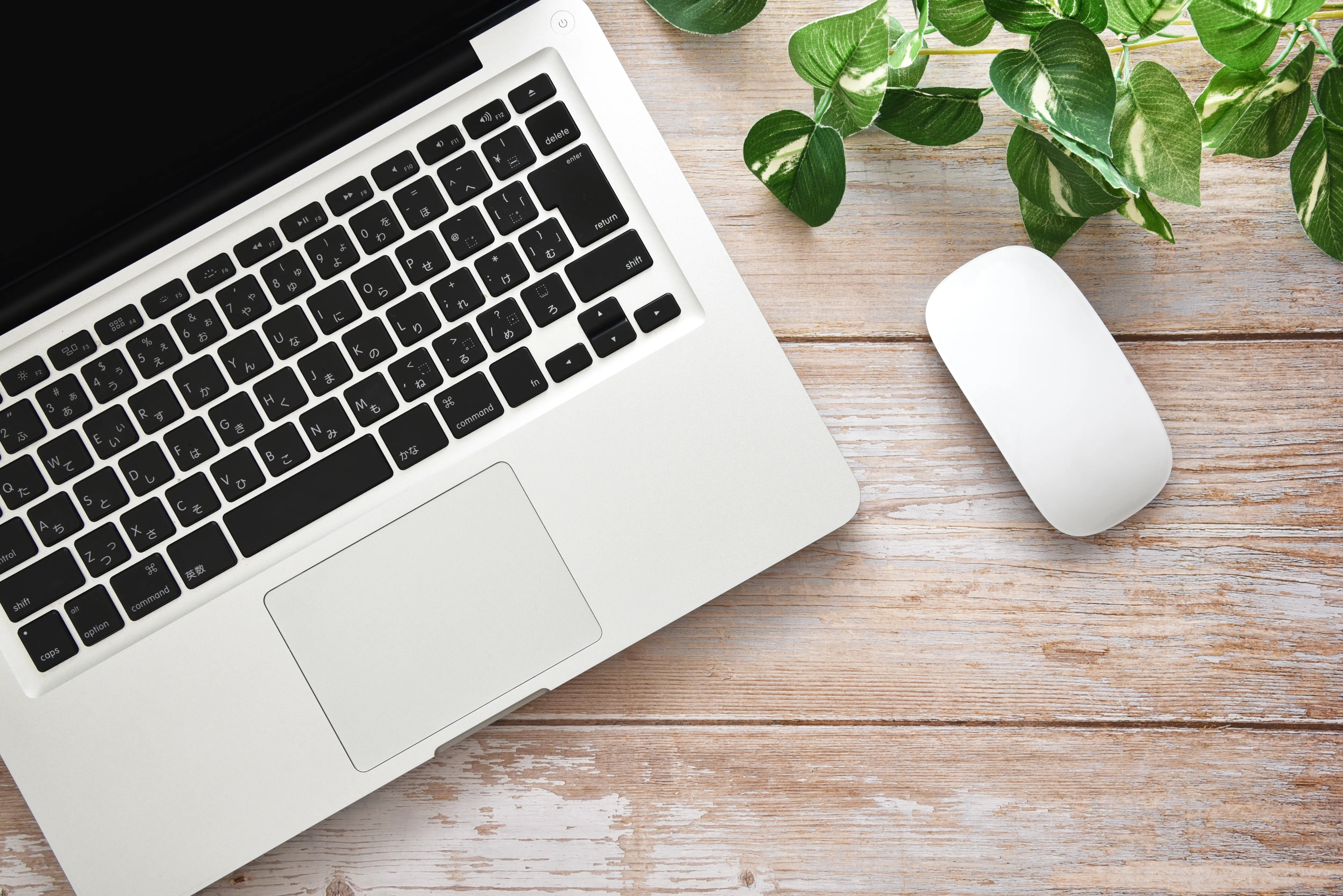 木目デスクにノートパソコンとマウス